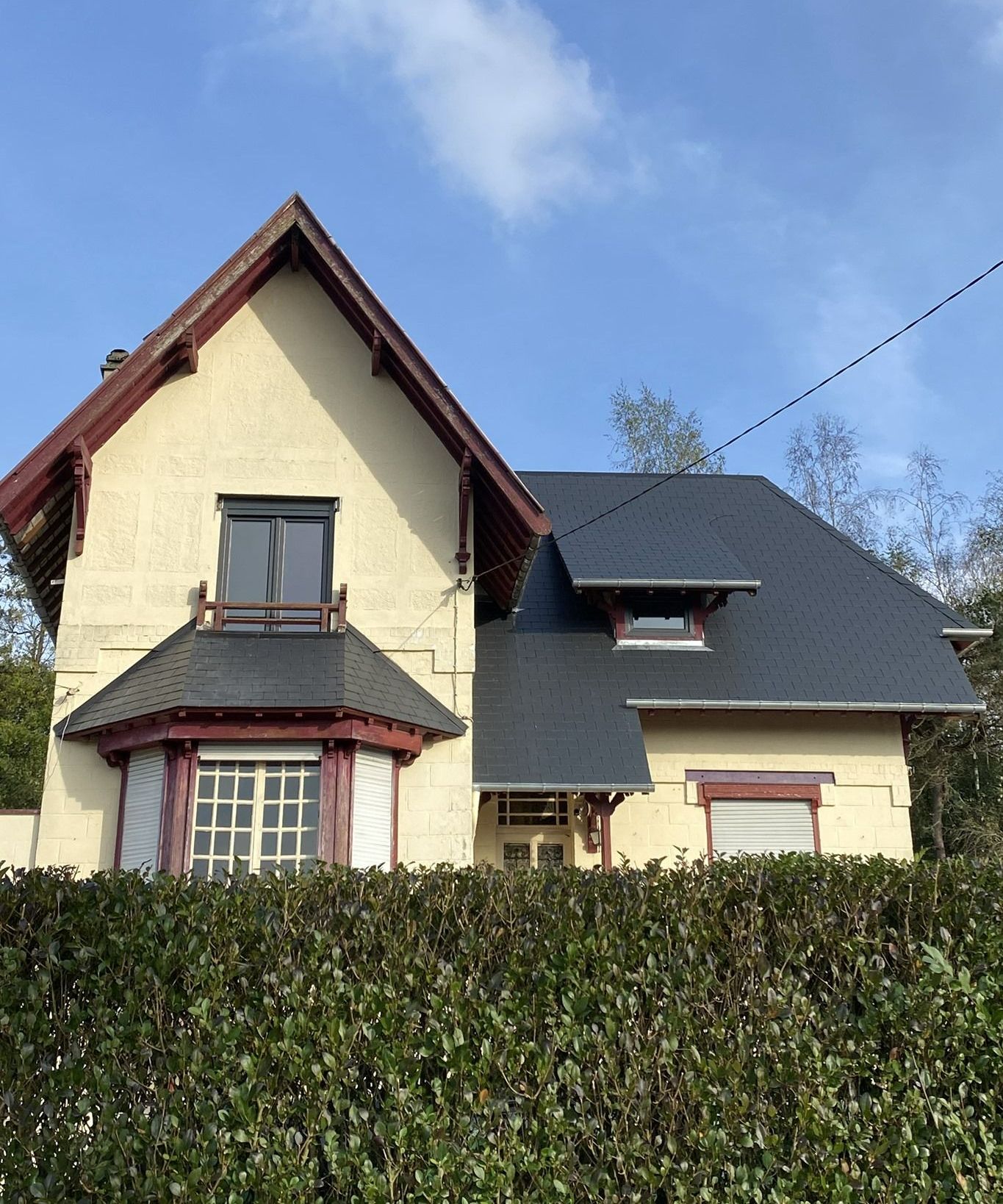 Une maison derrière une haie.