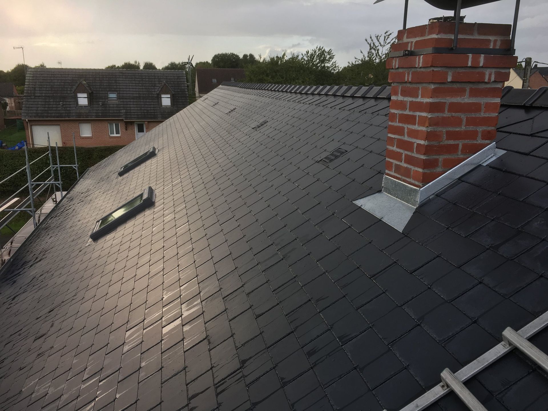 Une toiture en ardoise avec une cheminée en briques.