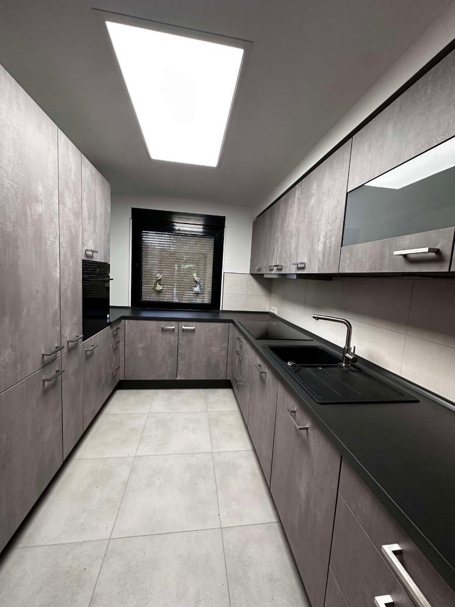 Eine Küche mit Spüle, Schränken und Fenster.