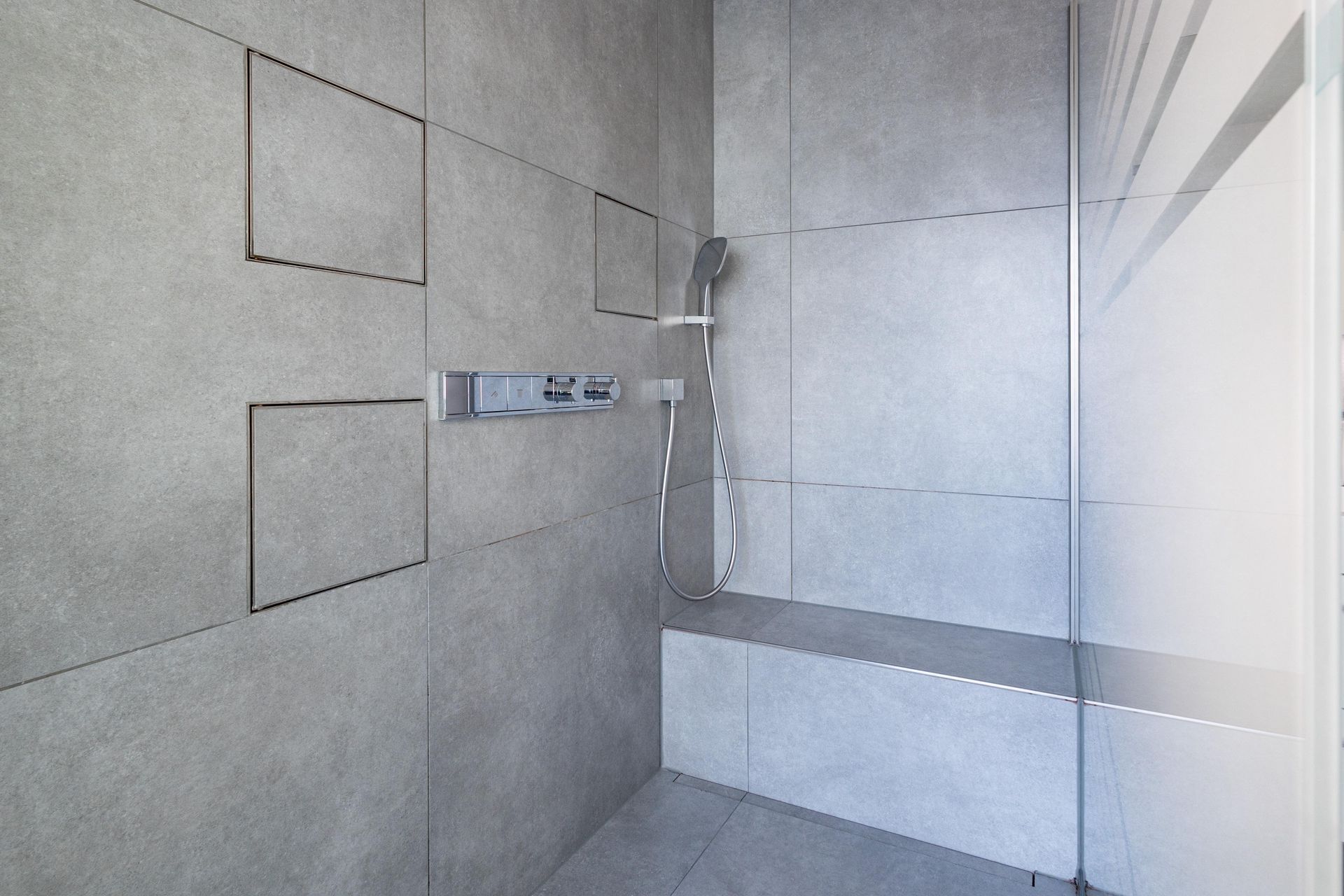 Ein Badezimmer mit ebenerdiger Dusche und Sitzbank.