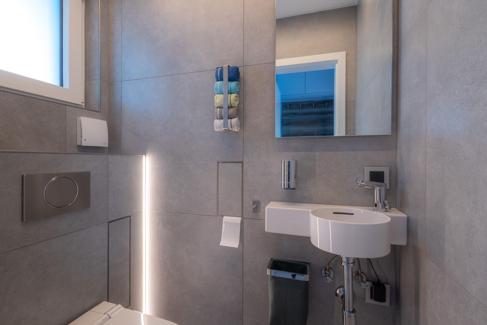 Ein Badezimmer mit Waschbecken, Toilette und Spiegel vom HSK-Handwerkszentrum