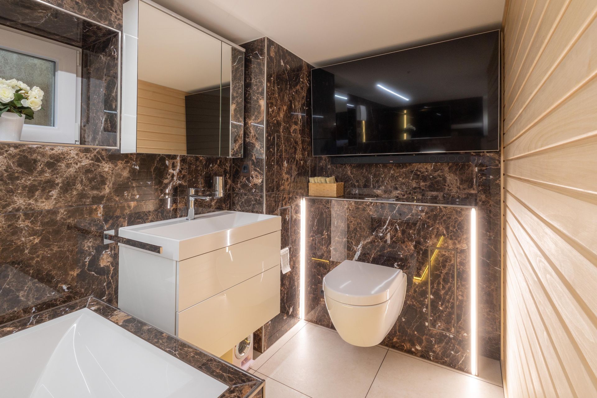 Ein Badezimmer mit Toilette, Waschbecken, Spiegel und Fernseher.