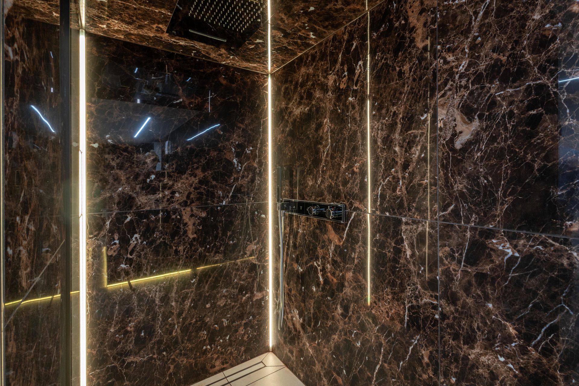 Ein Badezimmer mit Marmorwänden und ebenerdiger Dusche.