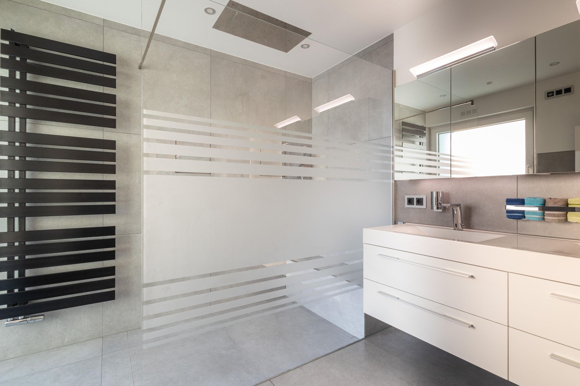 Ein Badezimmer mit ebenerdiger Dusche, Waschbecken und Spiegel vom HSK-Handwerkszentrum