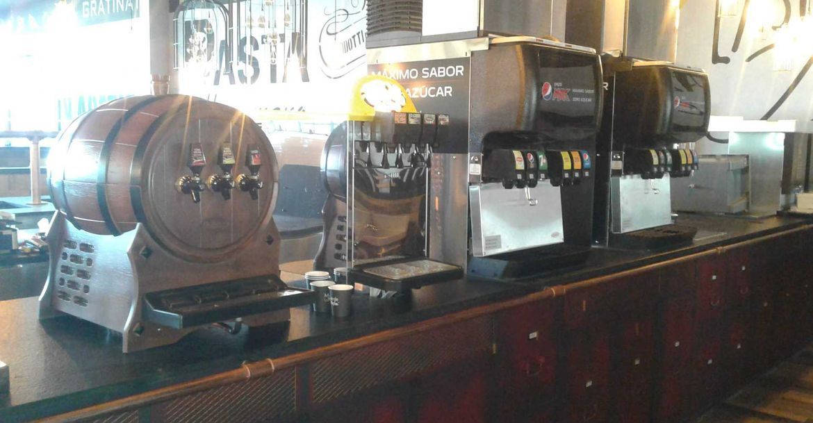 Una fila de máquinas de refrescos están alineadas en un mostrador en un restaurante.