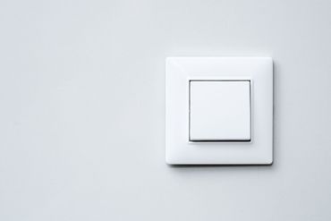 Interrupteur blanc sur un mur gris clair.