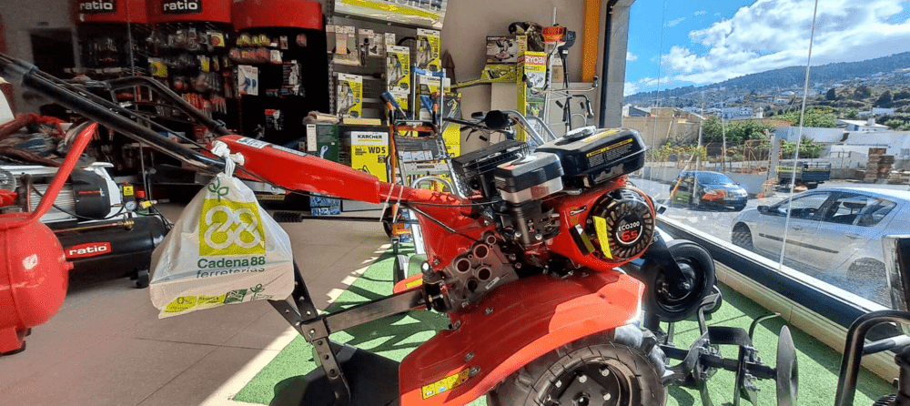 Un tractor rojo está estacionado en un garaje al lado de una ventana.