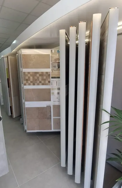 Una exhibición de azulejos en una tienda con una planta al fondo.