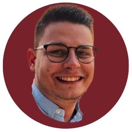 Personne souriante portant des lunettes et une chemise bleu clair sur un fond circulaire bordeaux