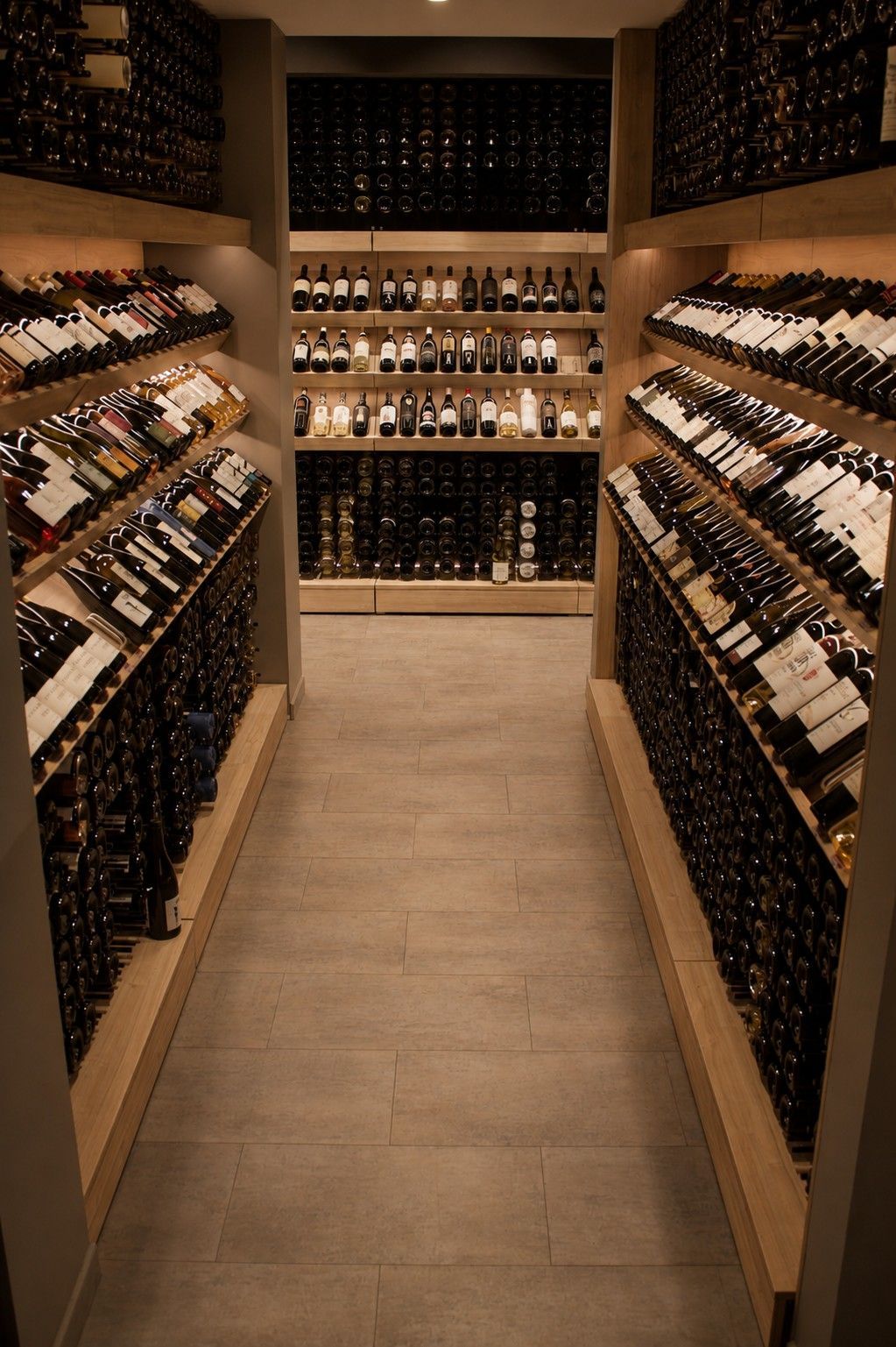 Allée étroite de la cave à vin avec des étagères en bois remplies de bouteilles de vin des deux côtés