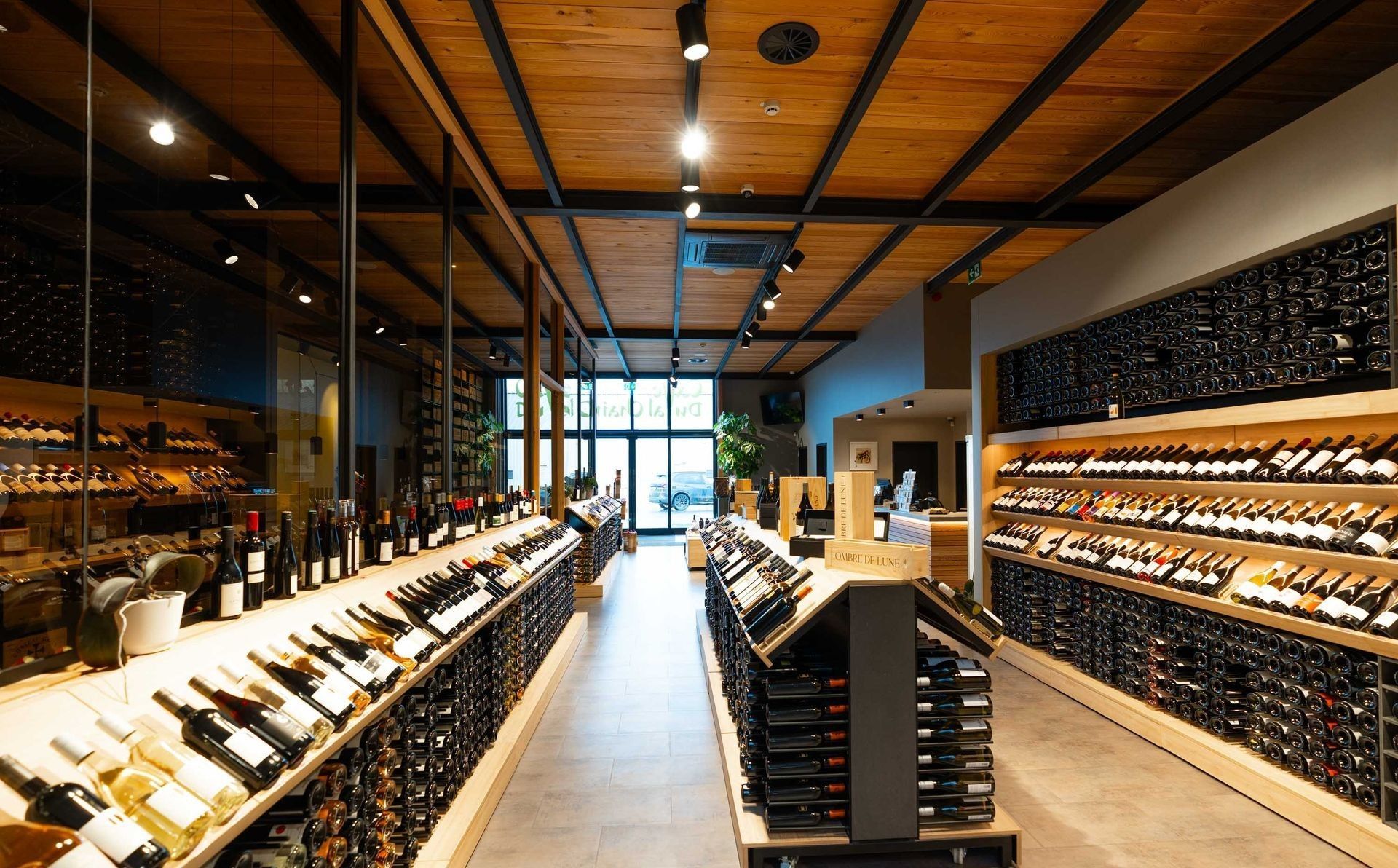 Allée d'une cave à vin avec des étagères de bouteilles et un plafond en bois chaleureux