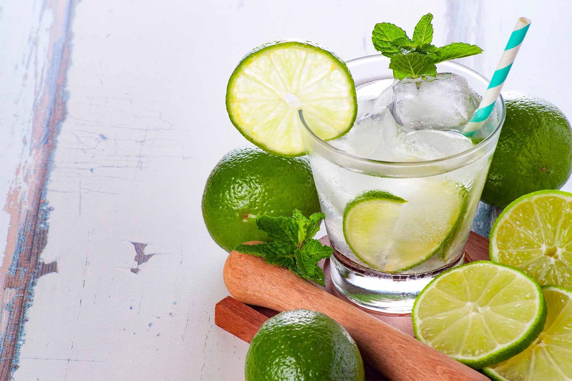 Verre de mojito entouré de citrons et tranches de citron verts