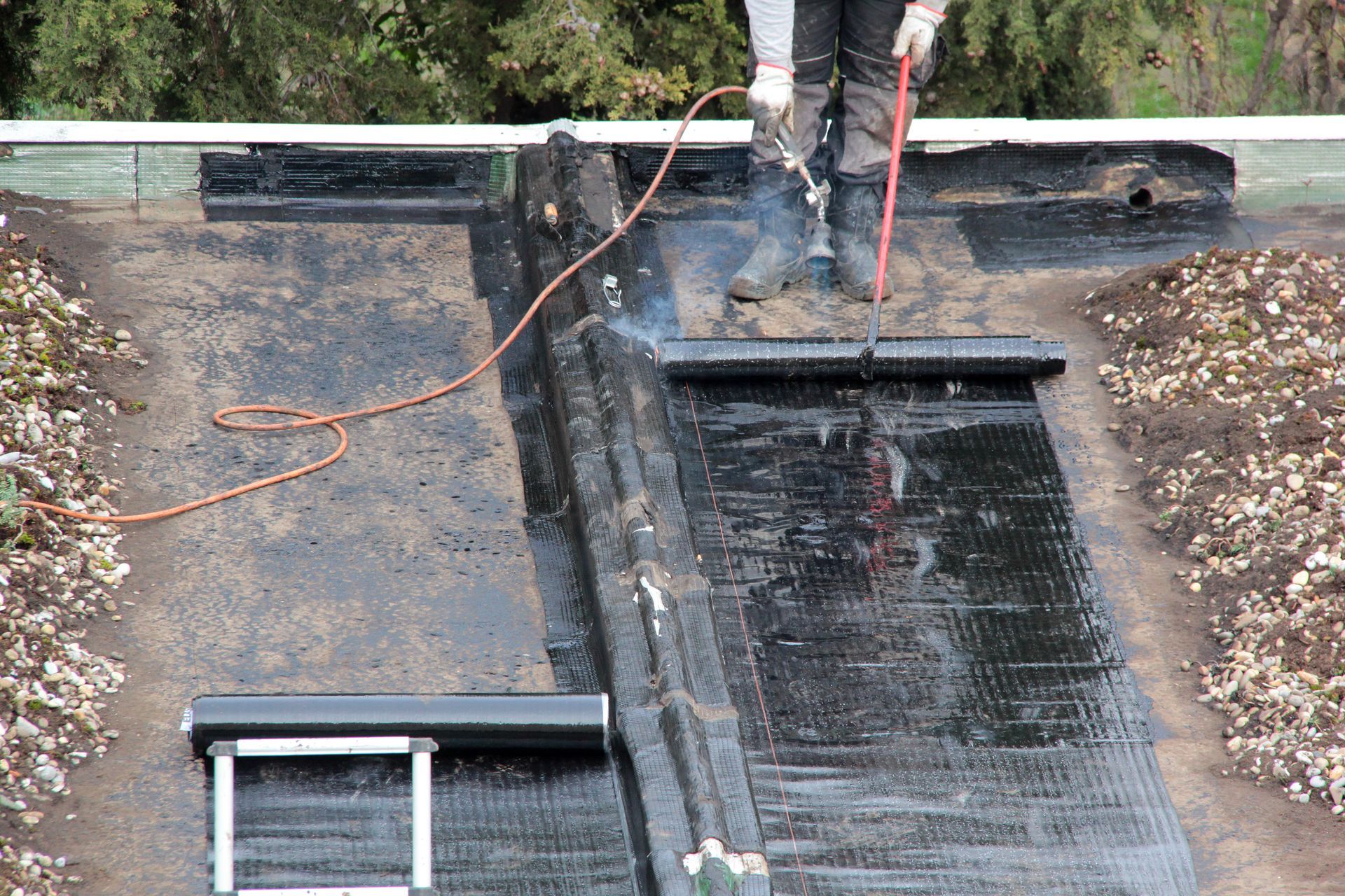 Ouvrier réalisant l'étanchéité d'un toit plat lors de travaux de rénovation