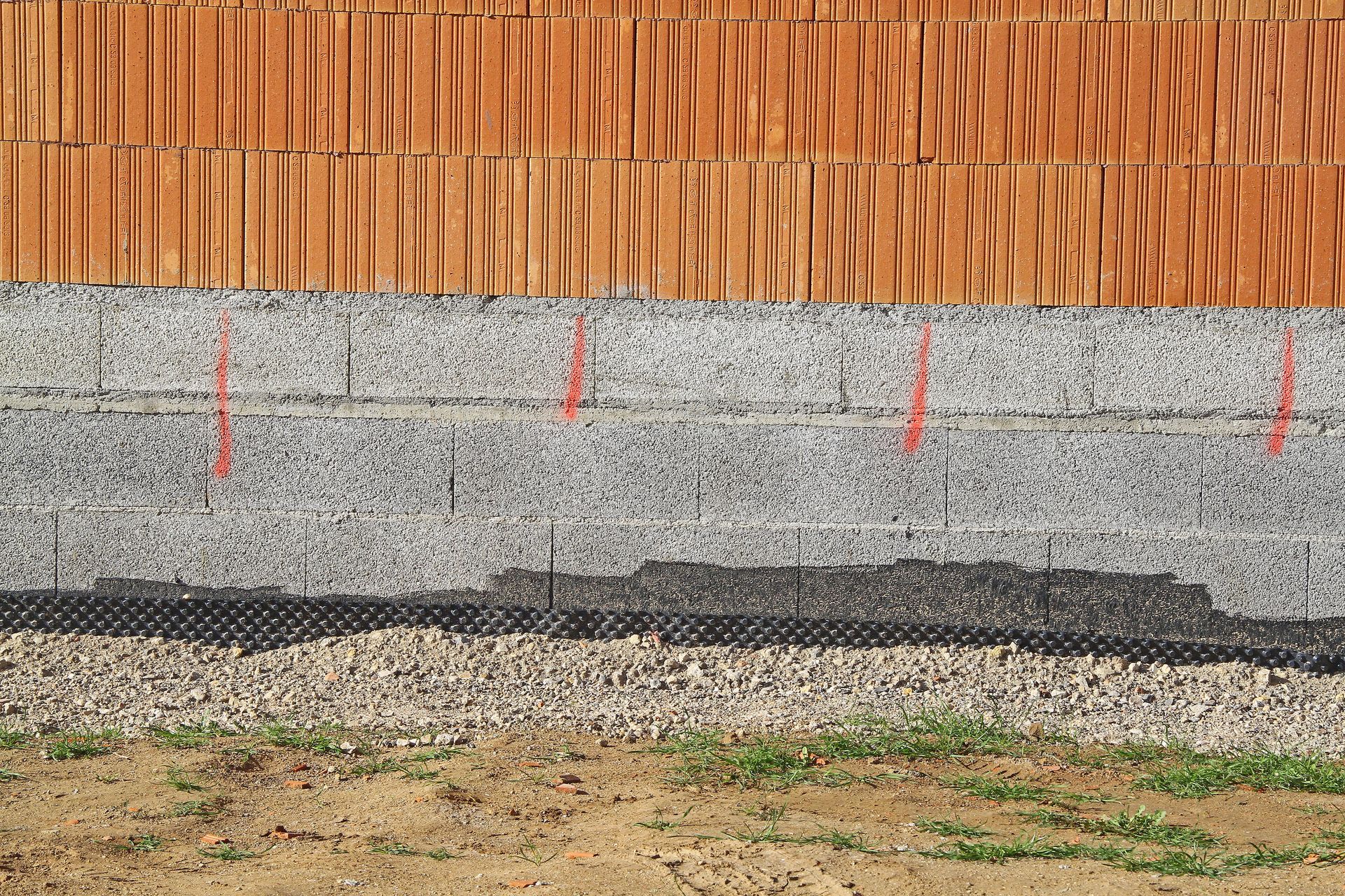 Mur en béton et en brique enterré avec des matériaux d'étanchéité sur la partie inférieure