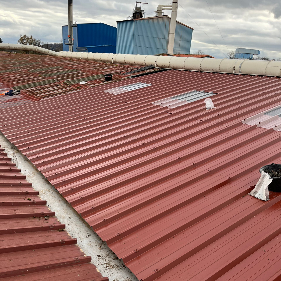 Toiture en tôle ondulée rouge avec conduits et aérations, vue du dessus dans une zone industrielle