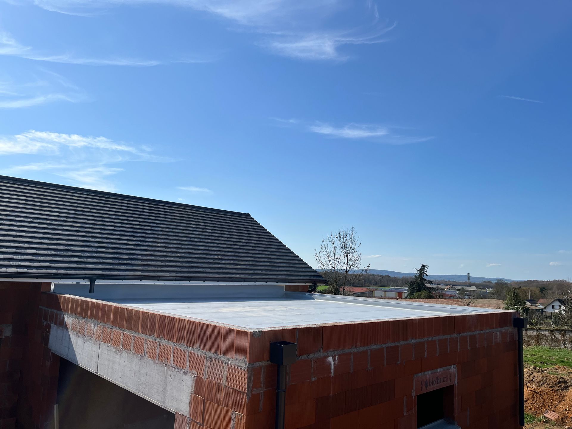 Structure en briques au toit plat et blanc sous un ciel bleu clair