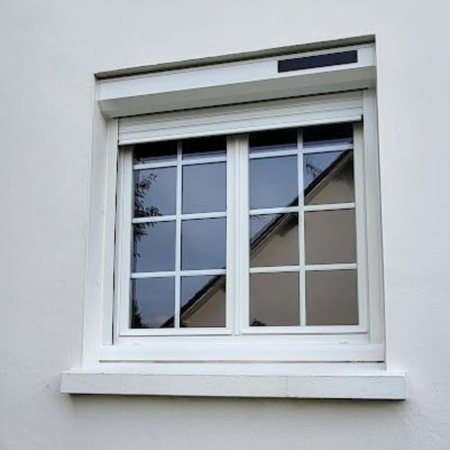 Maison en briques avec toit gris, fenêtres et pignons à ossature bois claire.