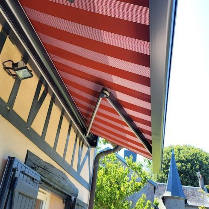 Auvent à rayures rouges et blanches s'étendant depuis un bâtiment à structure noire.