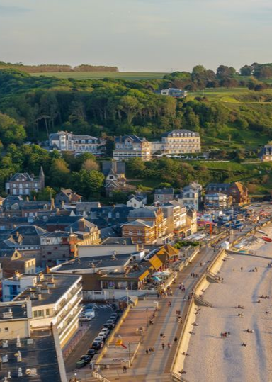 Un portail d'allée gris foncé, flanqué de piliers en pierre, mène à une maison.