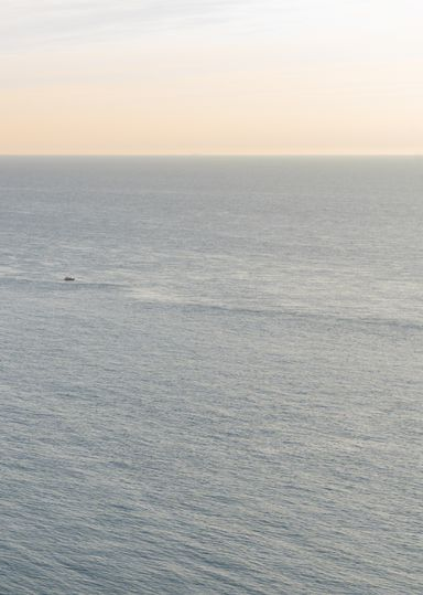 Petit balcon avec rambarde en métal noir, sol en pierre et vue sur la verdure.