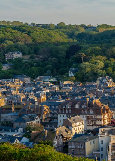 Un portail d'allée gris foncé, flanqué de piliers en pierre, mène à une maison.