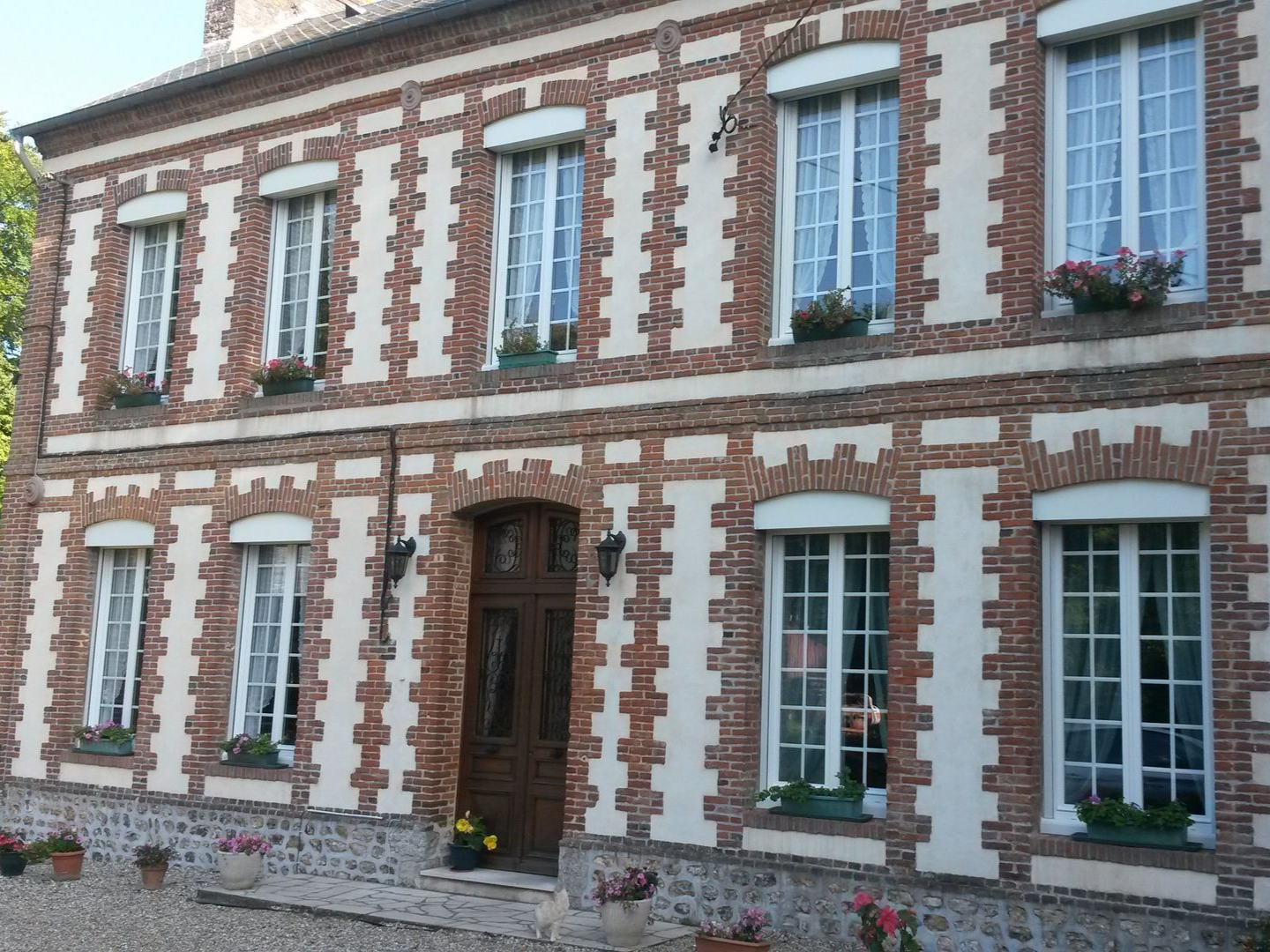 Bâtiment en briques de deux étages avec un mortier couleur crème, des fenêtres et une porte en bois.