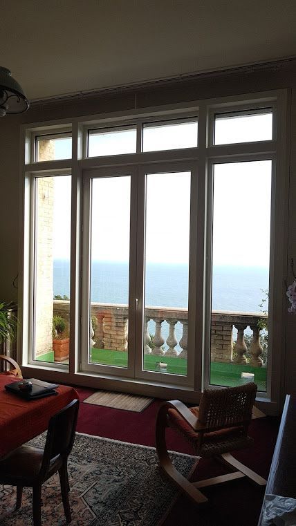 Grandes fenêtres donnant sur la mer, avec un balcon et un aménagement intérieur.