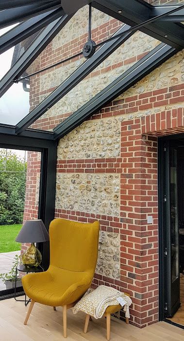 Fauteuil jaune dans une véranda en briques et en verre.