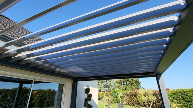 Pergola à lattes horizontales réglables ; aménagement extérieur sous un ciel bleu.