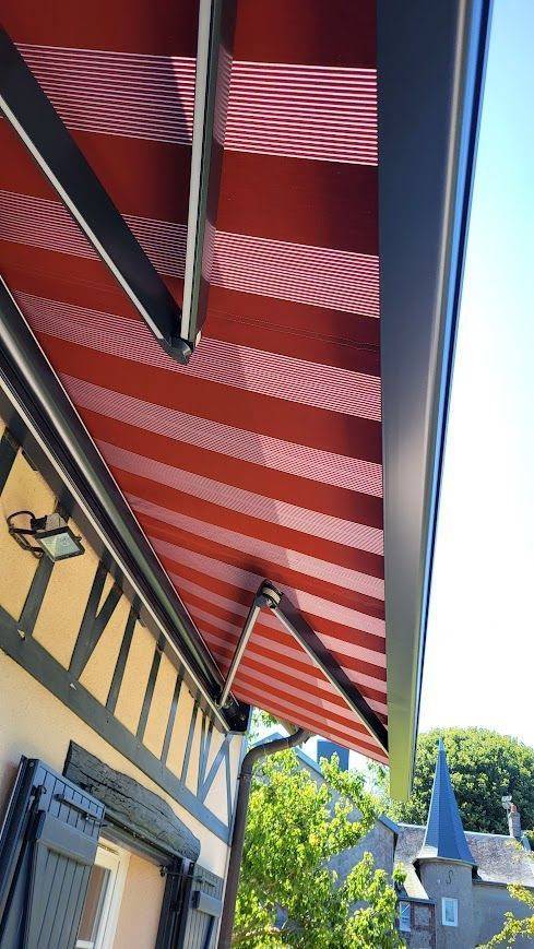 Auvent à rayures rouges et blanches s'étendant depuis un bâtiment à structure noire.