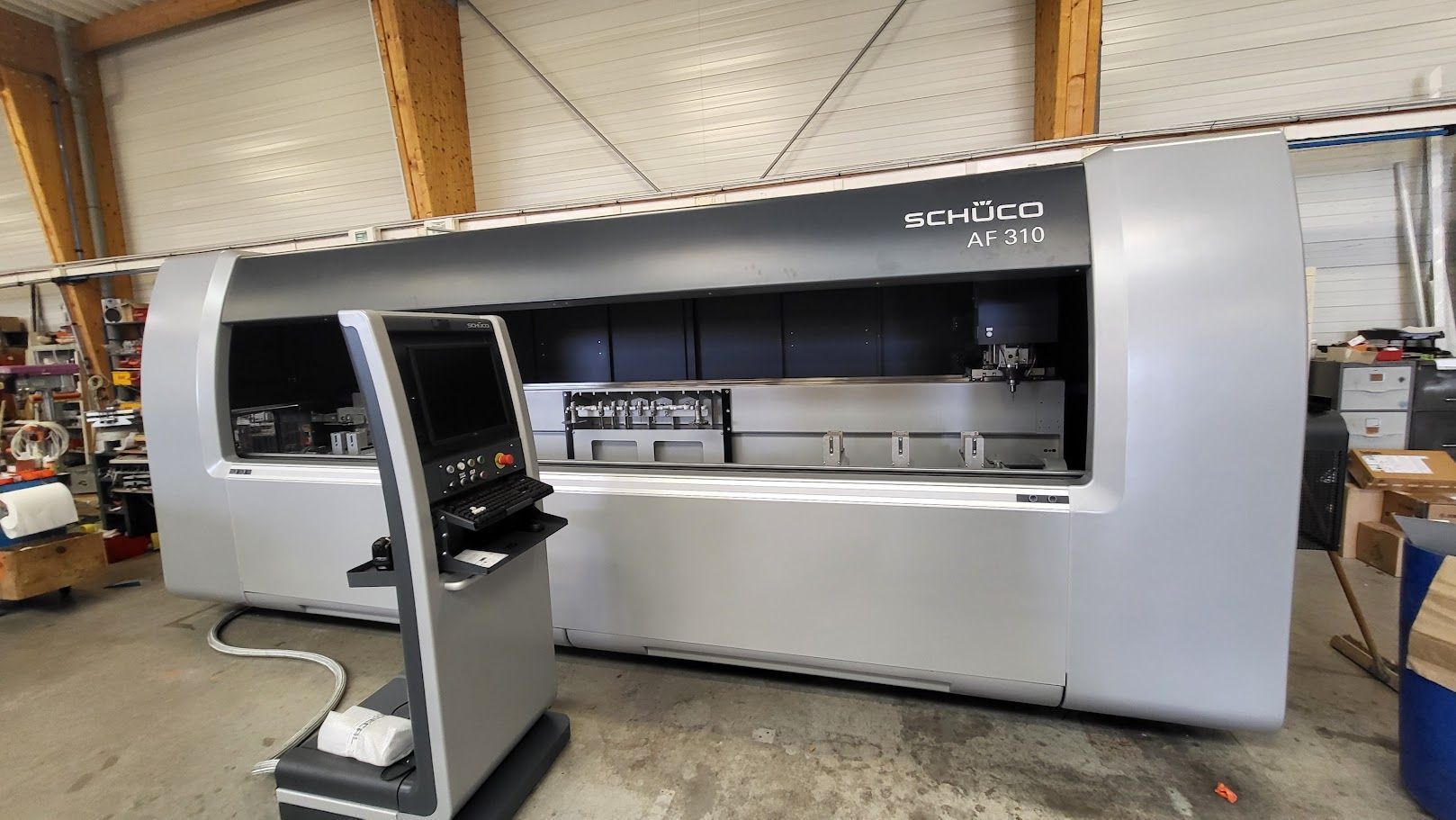 Grosse machine industrielle grise avec un panneau de commande dans un atelier.