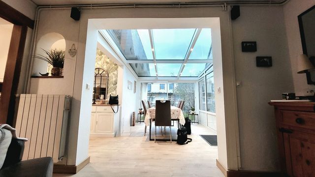 Vue intérieure d'une salle à manger avec un plafond en verre et une table dressée pour un repas.