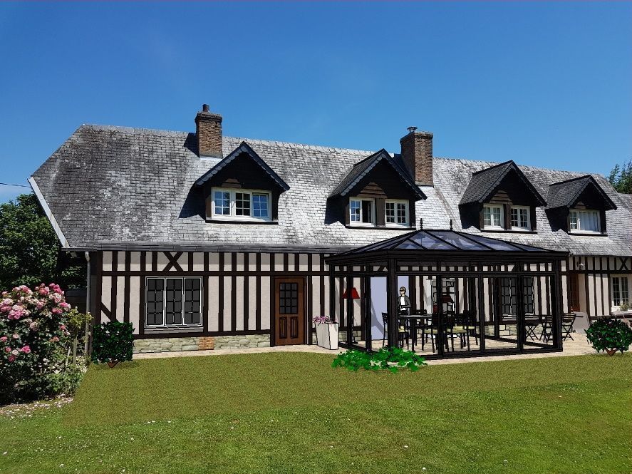 Charmante maison de campagne française avec colombages, lucarnes et pergola au-dessus d'un coin repas par une journée ensoleillée.
