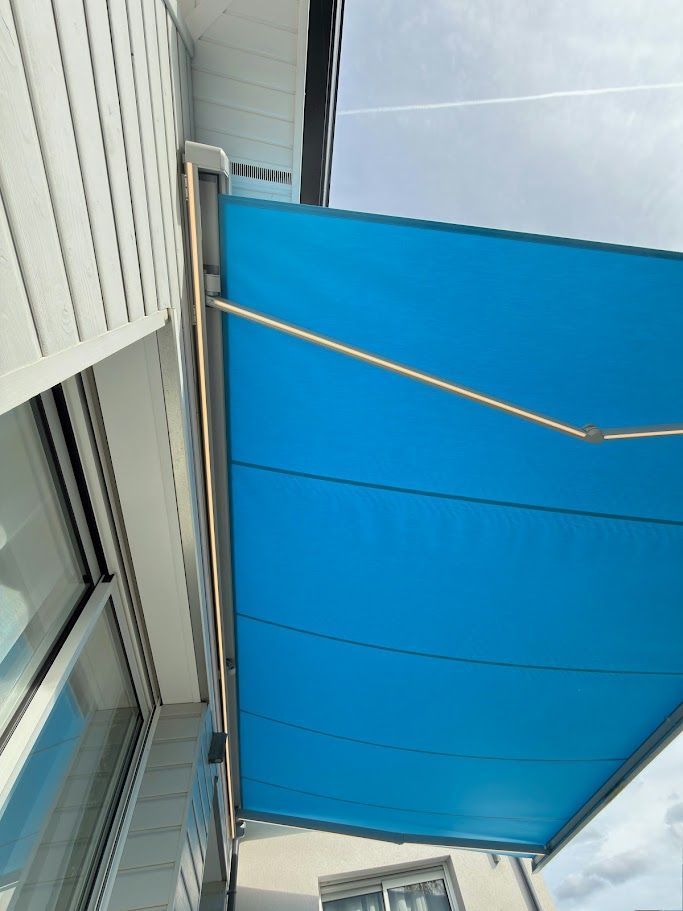 Un auvent bleu s'étend depuis un bâtiment blanc.