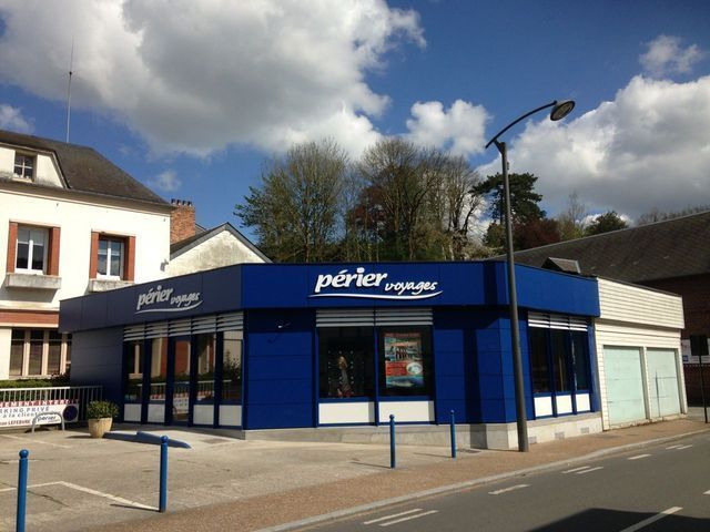 Un bâtiment bleu de l'agence de voyages Perier Voyages par une journée ensoleillée.