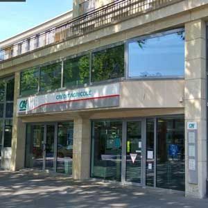 Façade de la banque Crédit Agricole avec de grandes vitrines et une enseigne.