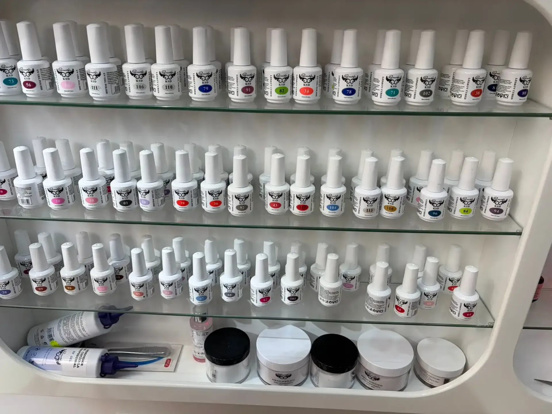 Frascos de esmalte de uñas en los estantes de un salón. Frascos blancos con etiquetas de caras de perro de varios colores.