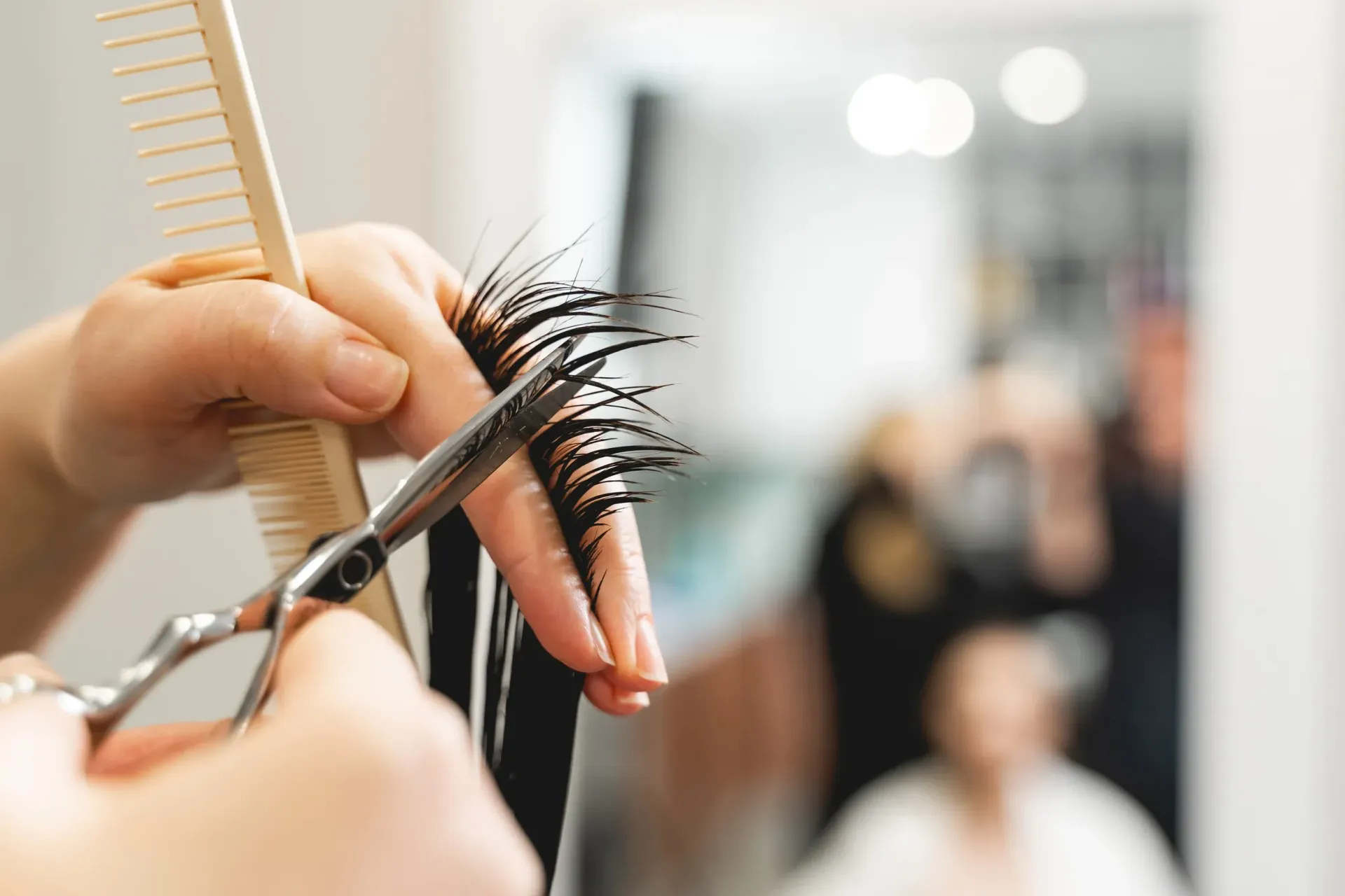Peluquero cortando el pelo con tijeras y peine en un salón, reflejado en un espejo.