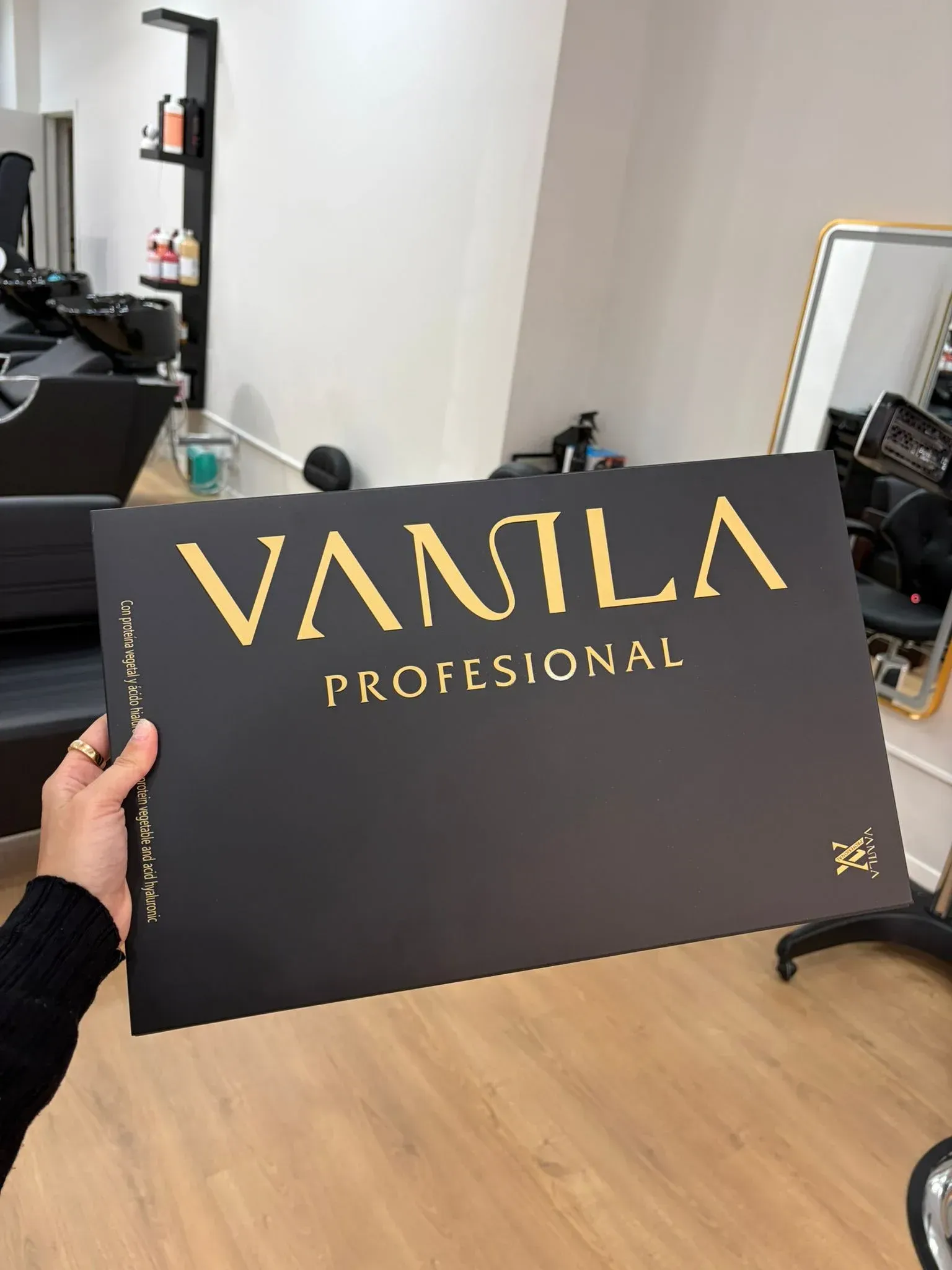 Persona sosteniendo un cartel negro con texto dorado: 