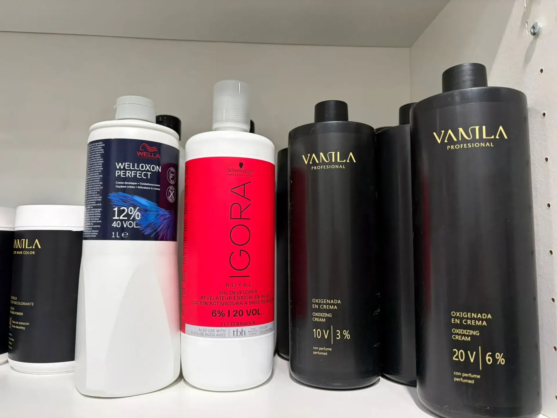 Botellas de productos para el cabello en un estante blanco. Etiquetas que indican 