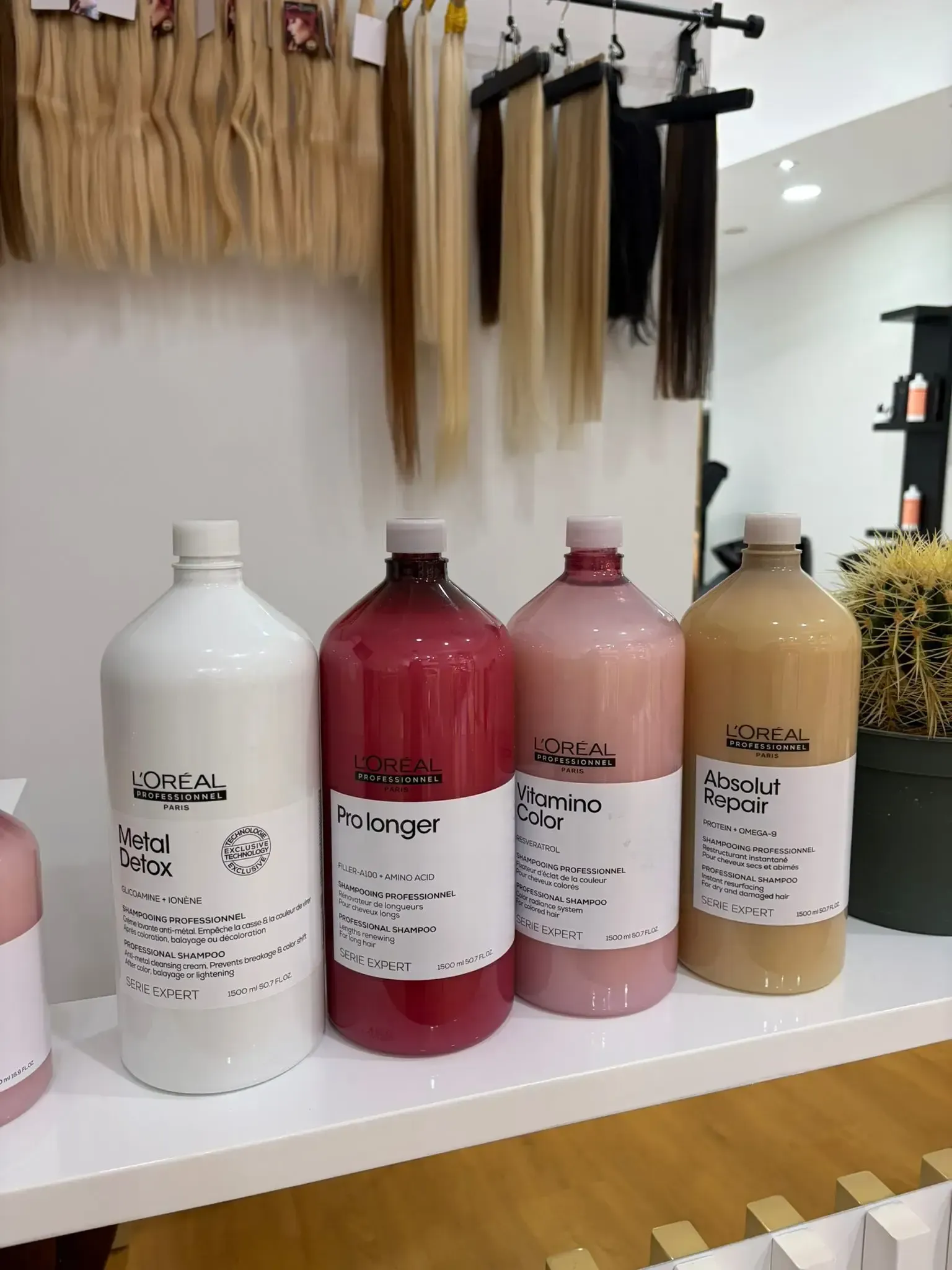 Botellas de productos para el cabello de diferentes colores y extensiones de cabello colgadas en una tienda.