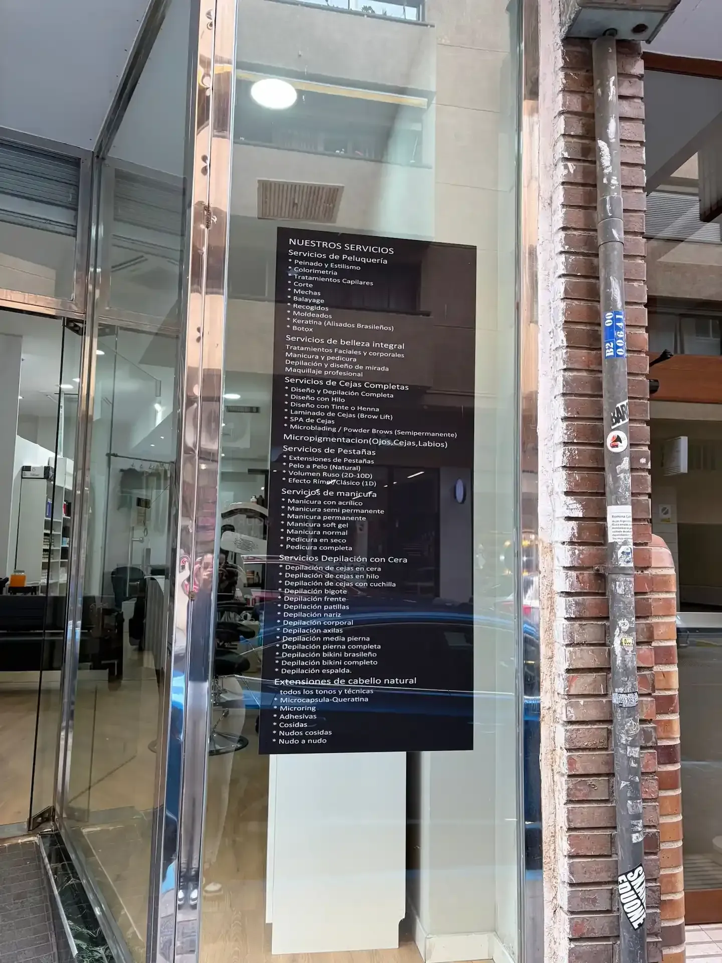 Escaparate con un letrero oscuro con texto blanco en una ventana. Metal reflectante y ladrillo enmarcan el cristal.