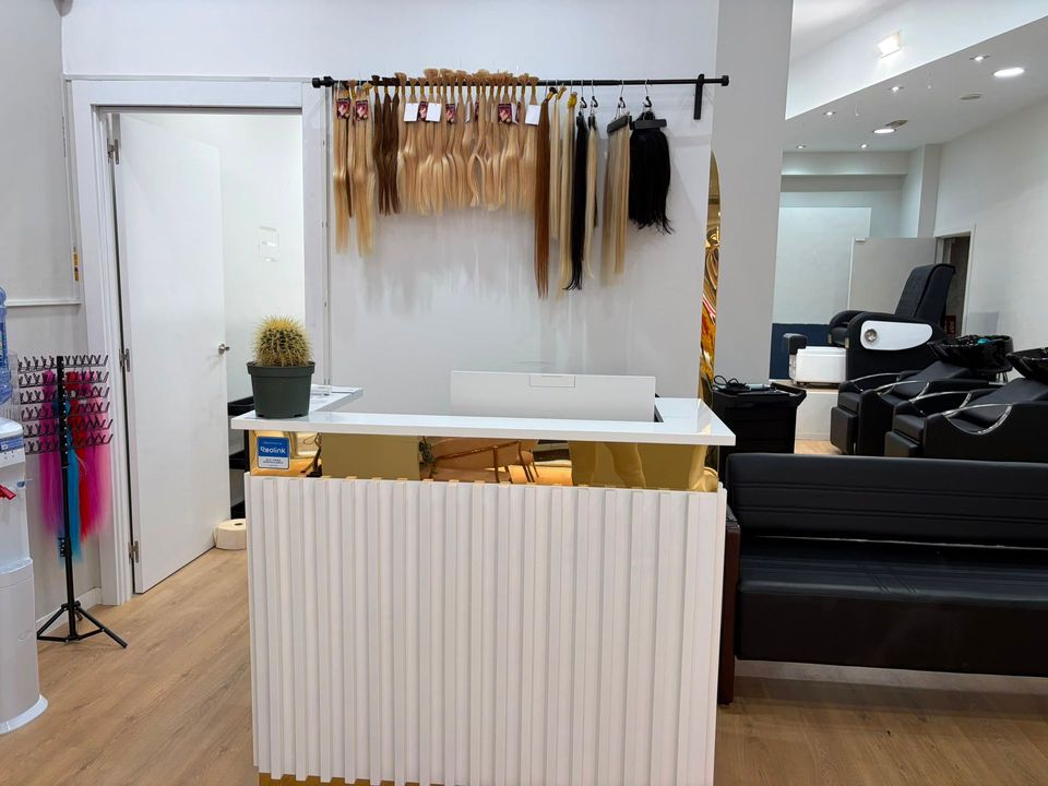 Sala de tratamientos estéticos con mesa de masajes beige, estanterías y lámpara de trabajo.