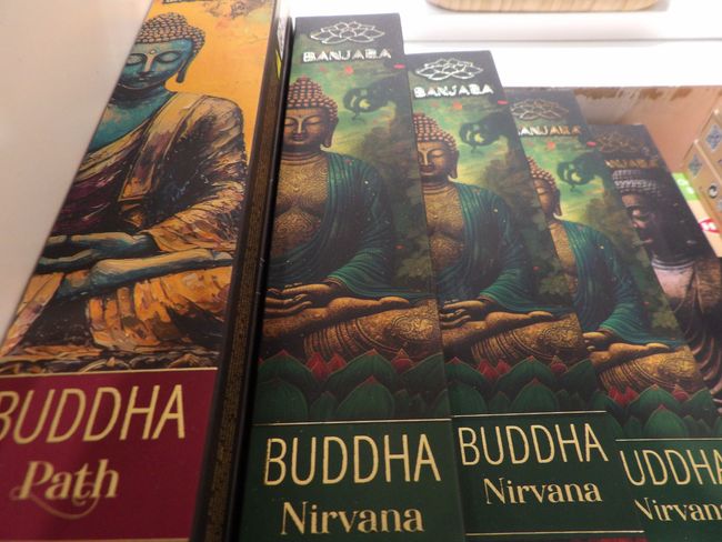 Varios libros con temática budista, de portadas verdes y doradas, apilados en un estante.
