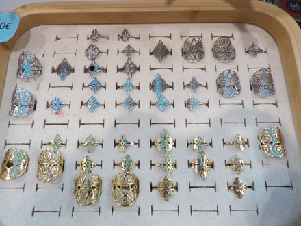 Bandeja con variadas piezas de joyería de plata y oro brillantes, dispuestas en filas sobre una superficie de madera.