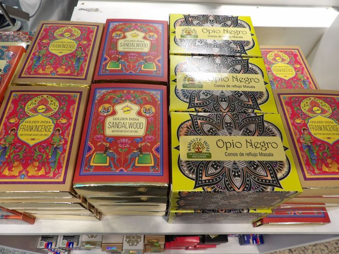 Artículos empaquetados de colores apilados en un estante de la tienda, incluyendo diseños ornamentados en rojo, amarillo y negro.