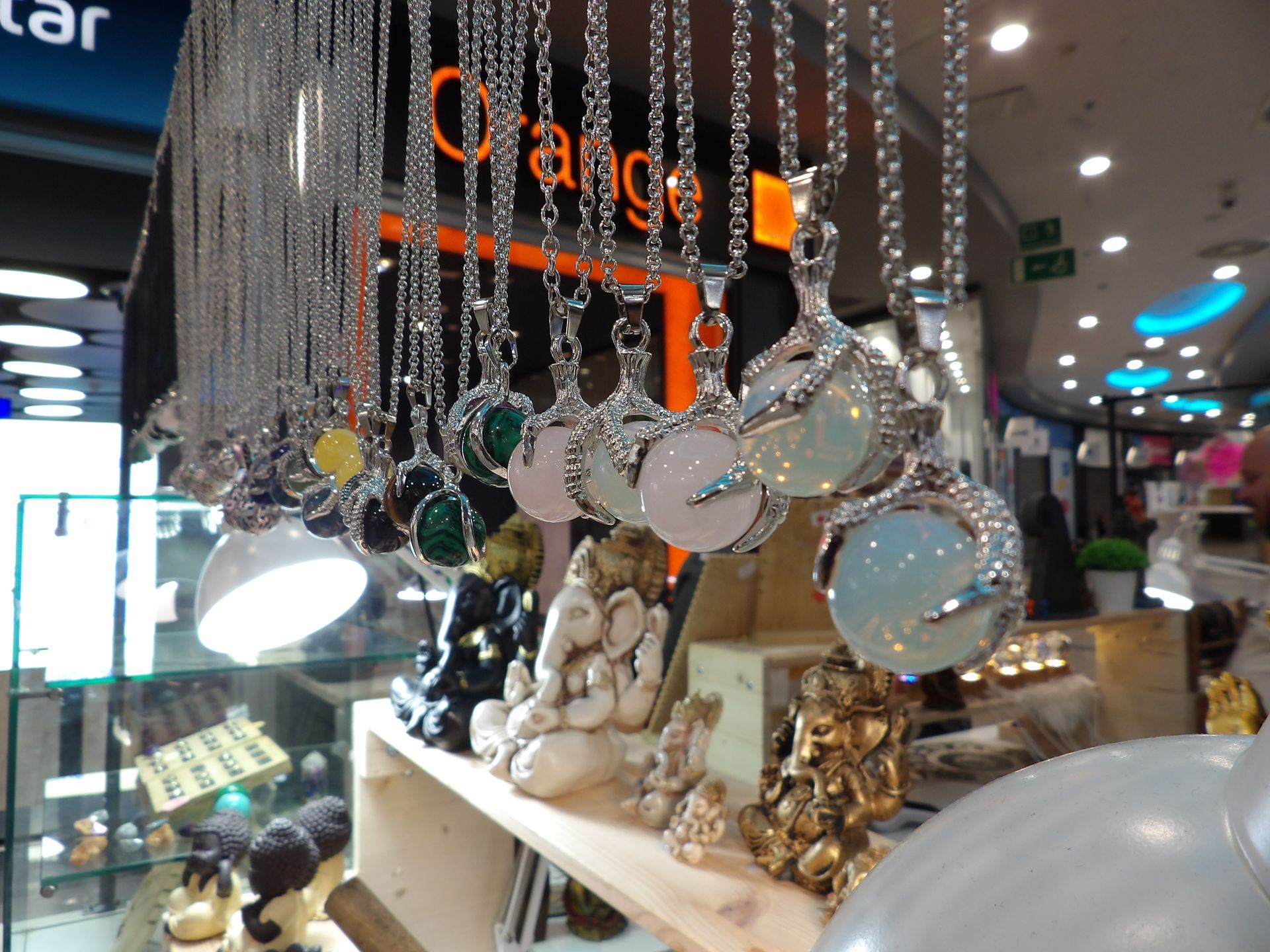 Adornos y figuritas de cristal colgantes decorativos expuestos en el escaparate de una tienda con luces brillantes.