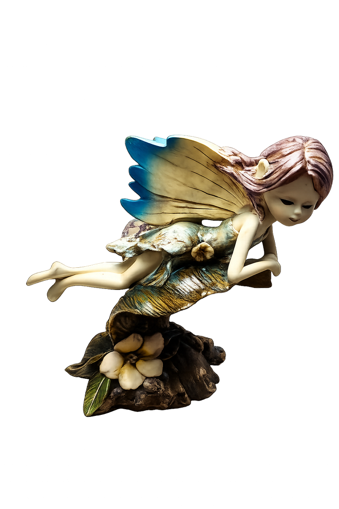 Figurita de hada con alas azules, apoyada en una roca, rodeada de flores.
