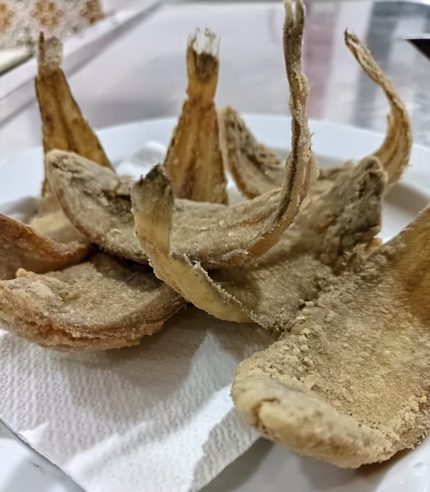 Champiñones fritos crujientes en un plato blanco cubierto con una toalla de papel.