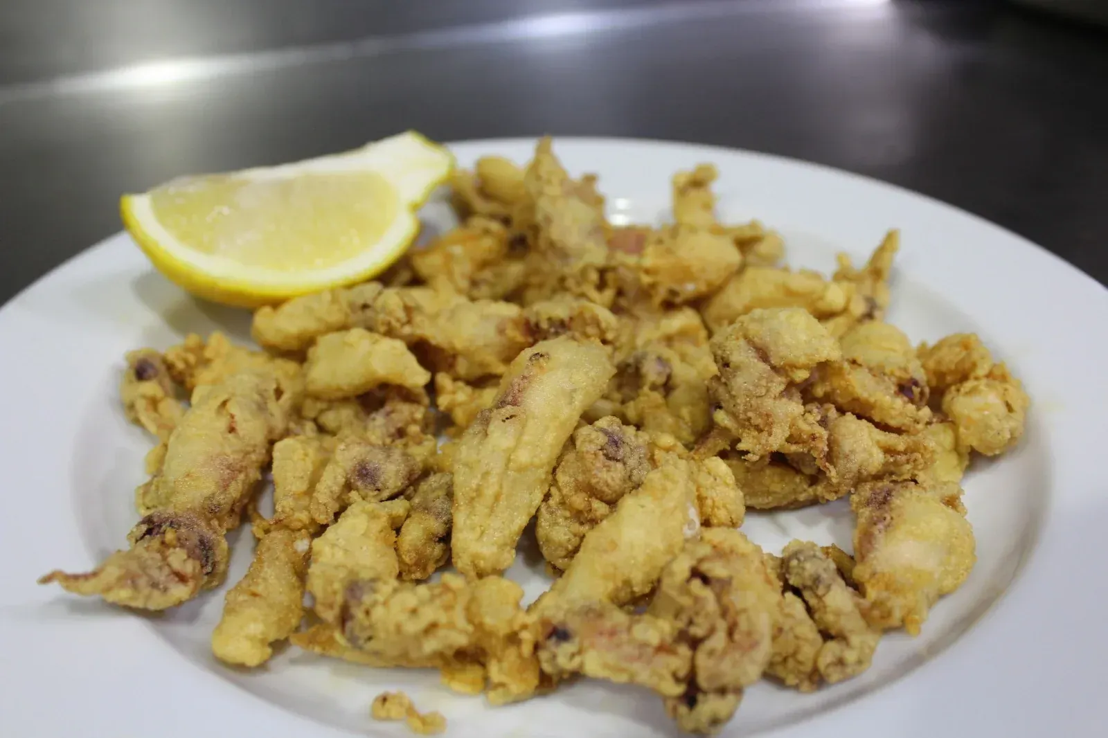 Calamares fritos con rodaja de limón en un plato blanco.